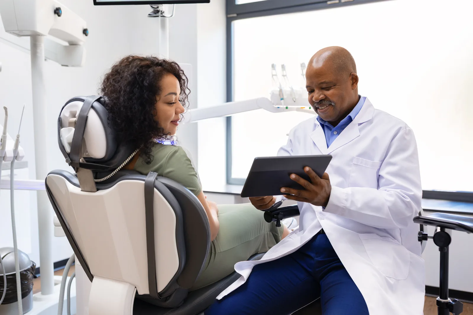 Dentist showing a patient information on a tablet in a clinic