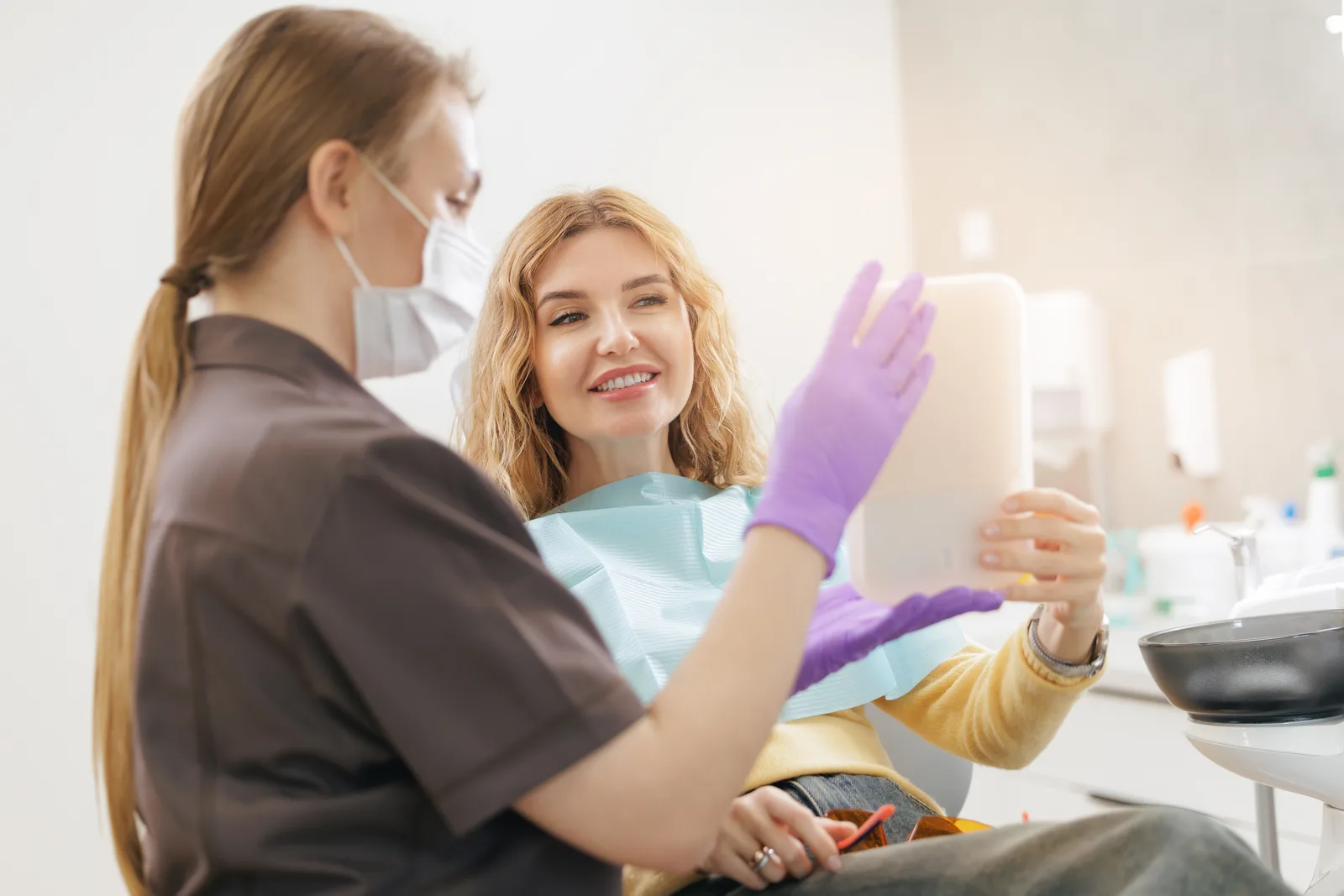 Patient holding a handheld mirror during a dental consultation