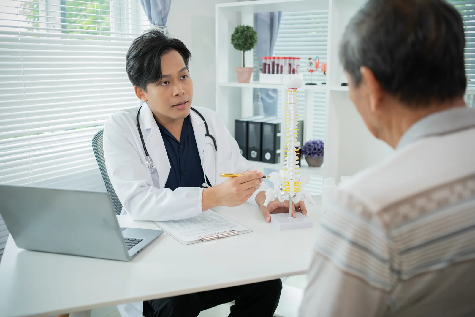 Orthopedic clinician explaining a spine model to a patient