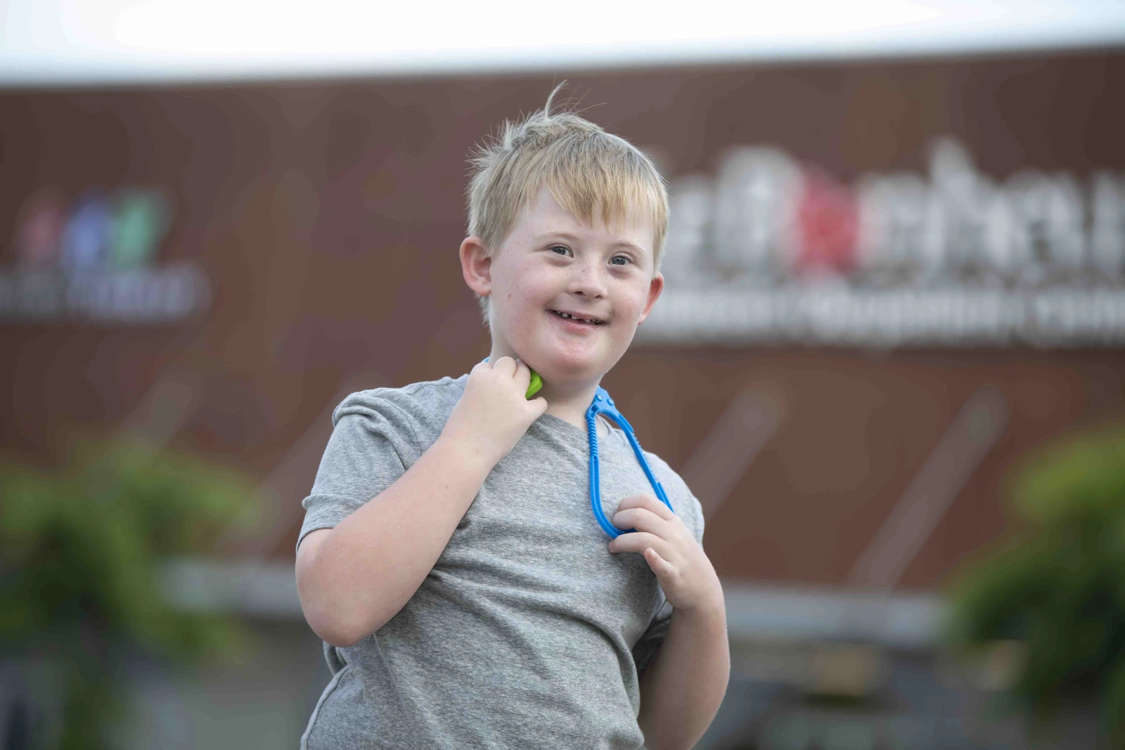 A smiling child holding a toy stethoscope outside Le Bonheur Children’s Hospital